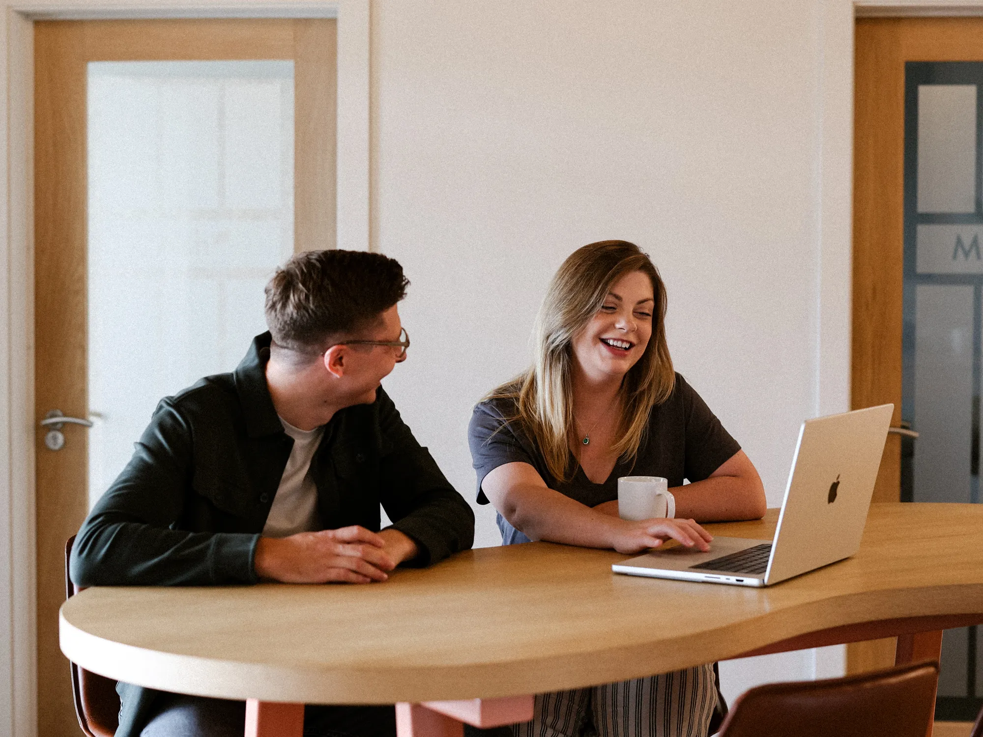 Ashton Lee Hudson laughing with a client over a laptop during a meeting